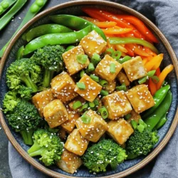 - 14 oz firm tofu, pressed and cubed - 2 tablespoons cornstarch - 3 tablespoons sesame oil - 1 bell pepper (any color), sliced - 1 cup broccoli florets - 1 carrot, julienned - 1 cup sugar snap peas - 3 green onions, chopped - 3 cloves garlic, minced - 1 tablespoon fresh ginger, minced - 2 tablespoons soy sauce (or tamari for gluten-free) - 1 tablespoon toasted sesame seeds - Salt and pepper to taste A serving of this dish has about 300 calories. It provides 15 grams of protein, 30 grams of carbohydrates, and 18 grams of fat. This makes it a balanced meal, packed with nutrients and flavor. You enjoy protein from tofu and fiber from vegetables. This stir fry is also low in calories, making it a great option for a healthy meal. To start, you need to press the tofu. This helps to remove extra water. Wrap the tofu in a clean towel and place a weight on top. Let it sit for about 15-20 minutes. This step is key for crispy tofu. Next, cut the pressed tofu into 1-inch cubes. Take the cubed tofu and toss it with cornstarch. Make sure all sides are coated. This cornstarch layer will give the tofu a great crunch. Now, heat 2 tablespoons of sesame oil in a non-stick skillet over medium-high heat. Wait until the oil is hot, then add the tofu cubes. Spread them in a single layer. Don’t overcrowd the pan. Fry the tofu for 3-4 minutes on each side. You want it golden and crispy. Once the tofu is cooked, remove it from the skillet and set it aside. In the same skillet, add the last tablespoon of sesame oil. Toss in the sliced bell pepper, broccoli florets, julienned carrot, and sugar snap peas. Stir-fry these veggies for 5-7 minutes. You want them tender but still crisp. After the veggies are ready, add minced garlic and ginger to the skillet. Stir-fry for one more minute. This will fill your kitchen with a lovely aroma. Now, return the crispy tofu to the skillet. Pour in the soy sauce and gently toss everything to mix. Cook for another 2 minutes to heat the tofu through. At this point, season with salt and pepper to taste. Garnish with chopped green onions and toasted sesame seeds. This adds flavor and makes your dish look great. For presentation, serve the stir-fry in a shallow bowl or on a plate. Add extra green onions and sesame seeds on top. Pair it with steamed jasmine rice or quinoa for a well-rounded meal. Enjoy your tasty, healthy dish! To get crispy tofu, first, you must press it. Pressing removes water. This step helps the tofu become crispy when cooked. Wrap the tofu in a clean kitchen towel. Place a weight on top for about 15 to 20 minutes. This simple trick makes a big difference. For frying, sesame oil is the best choice. It has a rich flavor and high smoke point. Use it to fry your tofu until it’s golden and crunchy. You can also mix it with a little vegetable oil if you want. Heat settings matter when stir-frying. Start with medium-high heat for the best results. This helps to cook your food quickly while keeping it crisp. If the heat is too low, the tofu and veggies may become soggy. Keep your vegetables crisp by not overcrowding the pan. Stir-fry in batches if needed. This gives each piece space to cook evenly. Stir-fry the veggies just until tender but still bright in color—about 5 to 7 minutes. To boost flavor, try adding extra seasonings. A dash of chili flakes can add heat. You can also use sesame seeds for more texture. If you like a sweet touch, a splash of honey or maple syrup works well. Pair your stir-fry with steamed jasmine rice or quinoa. These options balance the rich flavors of the dish. You can also serve it with a side of fresh salad to add crunch and freshness. {{image_2}} You can swap tofu for other proteins. Chicken works great here. Just cut it into bite-sized pieces and cook it until it’s golden. Beef is also a tasty choice. Use thin strips for quick cooking. Shrimp adds a light touch. Just make sure they turn pink and opaque. Each option brings a new taste while keeping the dish healthy. Feel free to change up the veggies. Zucchini or bell peppers add color and crunch. Cauliflower can replace broccoli for a different texture. Snow peas are a sweet alternative to sugar snap peas. You can also use bok choy for a crisp bite. Mix and match your favorites to make it your own. Switching sauces can change the whole dish. Try adding a spicy chili sauce for heat. A sweet and sour sauce can give it a tangy twist. You can also mix in nuts for crunch. Cashews or peanuts add a nice bite. Experiment with these flavors to keep things exciting! Store your crispy sesame tofu stir fry in an airtight container. Make sure it is cool before sealing. Place it in the fridge for up to three days. This keeps the flavors fresh and safe to eat. If you want to keep it longer, consider freezing it. To reheat, use a skillet on medium heat. Add a splash of water or oil to keep the tofu moist. Heat it for about five minutes, stirring gently. This method helps keep the tofu crispy. You can also use a microwave, but it may make the tofu less crunchy. Yes, you can freeze this dish! Make sure to let it cool completely first. Portion it into freezer-safe bags. Remove as much air as you can before sealing. It will stay good for up to three months. When you're ready to eat, thaw it in the fridge overnight before reheating. To make this dish gluten-free, swap the soy sauce for tamari. Tamari has a similar taste but is gluten-free. You can also check the cornstarch brand to ensure it’s gluten-free. For added flavor, consider using coconut aminos. This gives a nice sweet taste without gluten. Yes, you can prep parts of this dish ahead of time. Press and cube the tofu a day before. Store it in an airtight container in the fridge. Chop the vegetables too. Keep them in separate containers. This way, you can stir-fry quickly when you're ready to cook. This dish pairs well with steamed jasmine rice or fluffy quinoa. Both add a nice base to the meal. You can also serve it with a side of fresh salad. A light cucumber salad works great. If you're feeling adventurous, try it with some spring rolls. This blog post covered making a delicious Crispy Sesame Tofu Stir Fry. You learned about key ingredients, the cooking steps, and how to achieve the perfect texture. I shared tips to enhance flavor and provided variations to fit your taste. Storing leftovers and reheating techniques also help keep your dish fresh. In conclusion, enjoy this recipe any way you like. It’s simple, healthy, and satisfying. Experiment with your ingredients to make it your own!